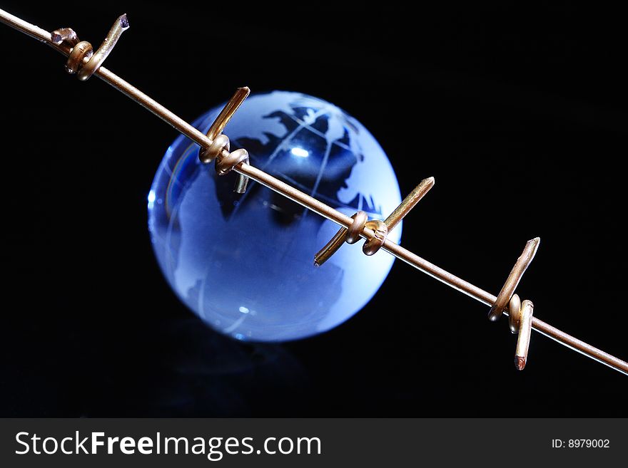 Close-up of barbed wire on dark background with blue globe. Close-up of barbed wire on dark background with blue globe