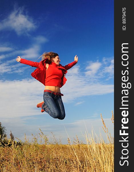 The girl jumps in the field against the sky. The girl jumps in the field against the sky