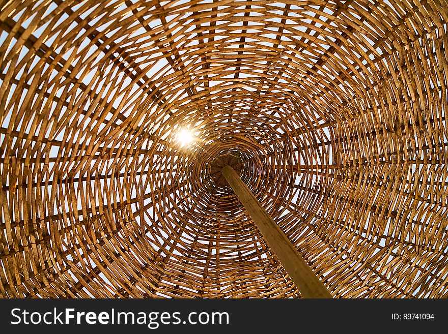 Abstract textures from wicker umbrella on wooden pole with sun shining through. Abstract textures from wicker umbrella on wooden pole with sun shining through.