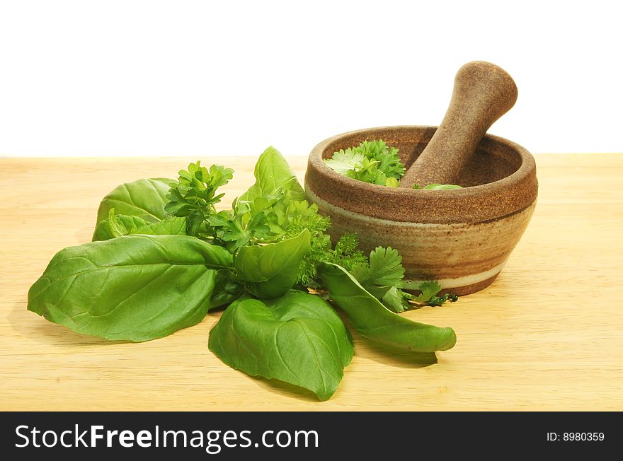 Pestle and mortar with fresh herbs on a wooden board. Pestle and mortar with fresh herbs on a wooden board