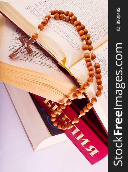 Open Holy Bible lying on stack of old books with glasses, cross and beads. Open Holy Bible lying on stack of old books with glasses, cross and beads