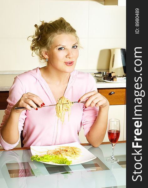 Happy beautiful woman at home in the kitchen eating spaghetti. Happy beautiful woman at home in the kitchen eating spaghetti