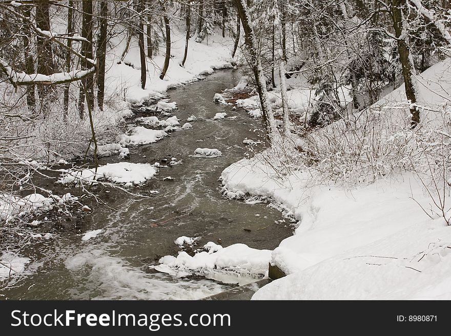Small river in winter forest. Trees are covered with fresh snow. Small river in winter forest. Trees are covered with fresh snow.