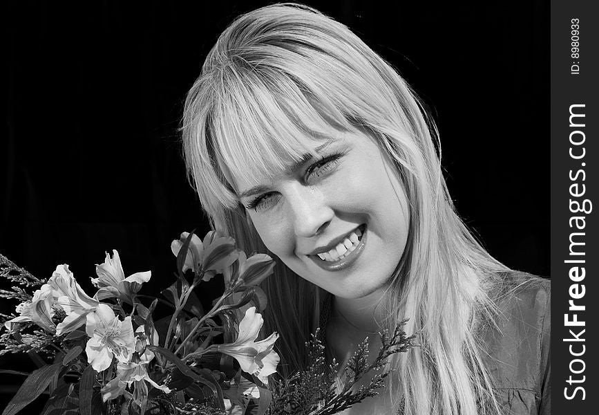 Black & White portrait of a beautiful blond girl holding a bouquet of flowers and smiling. Black & White portrait of a beautiful blond girl holding a bouquet of flowers and smiling