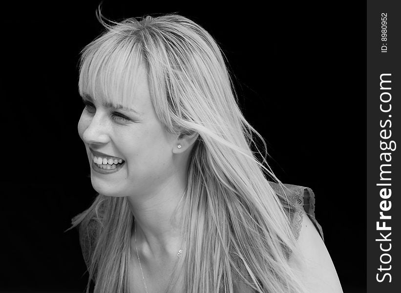 Black and White Portrait of a blond attractive woman smiling against black background