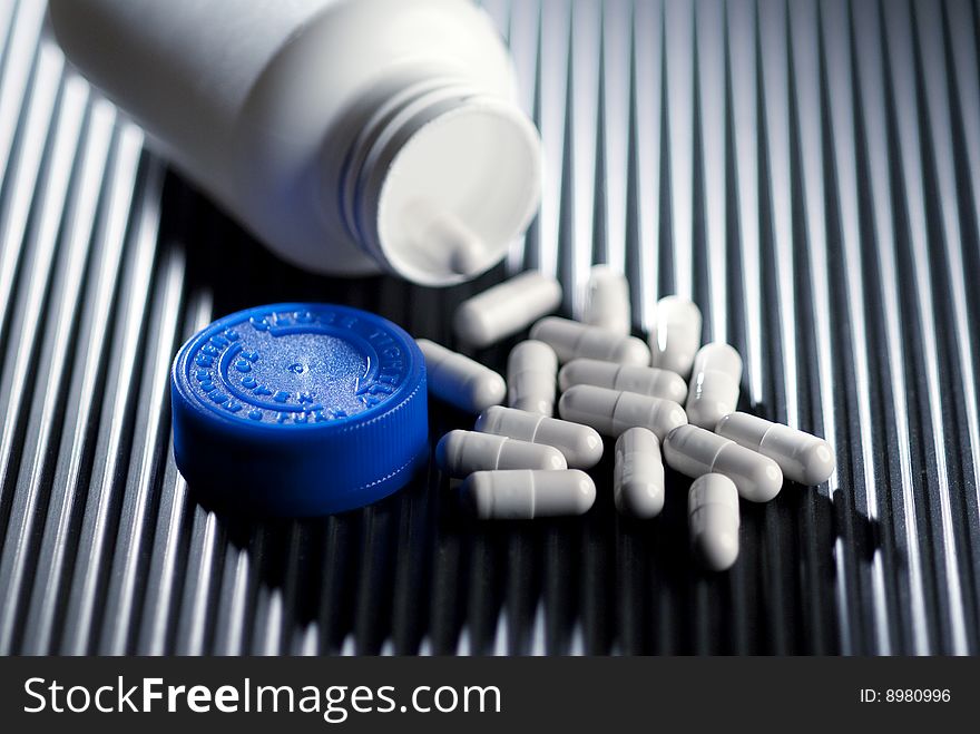 Prescription bottle and capsules on black surface. Prescription bottle and capsules on black surface