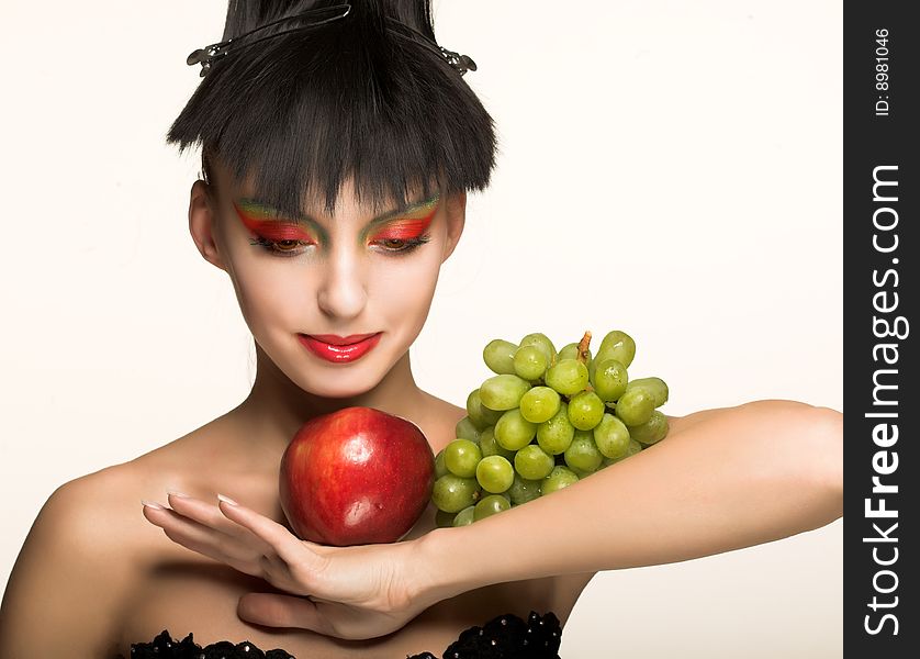 Portrait of pretty brunette with red apple and green grapes. Portrait of pretty brunette with red apple and green grapes