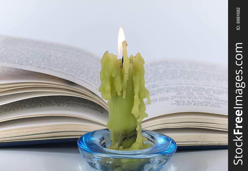 Candle and book on light background