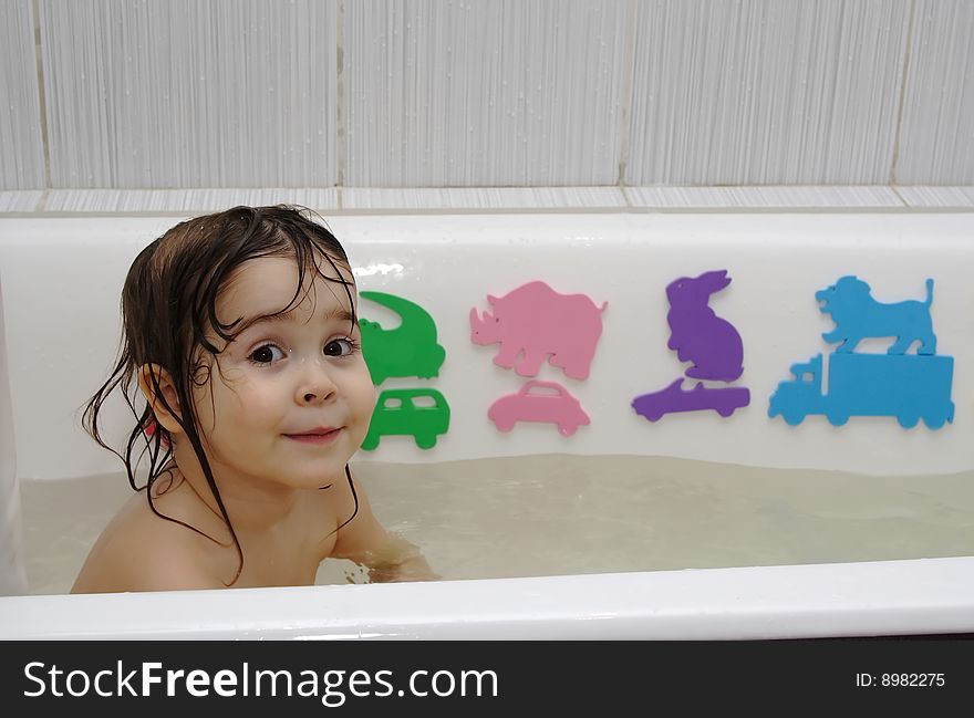 Little girl take a bath with toys