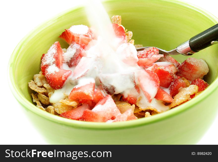 Bowl of corn flakes and fresh strawberries with milk being poured over them. Bowl of corn flakes and fresh strawberries with milk being poured over them.