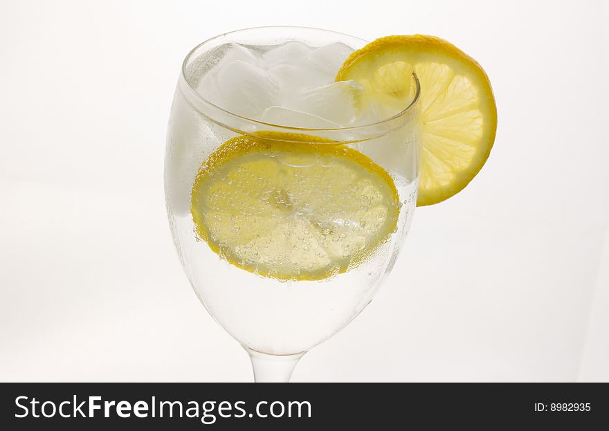 A glass of ice cold lemon drink with ice cubes. A glass of ice cold lemon drink with ice cubes