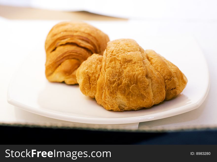 Two fresh croissant on white plate  - focus on close one. Two fresh croissant on white plate  - focus on close one
