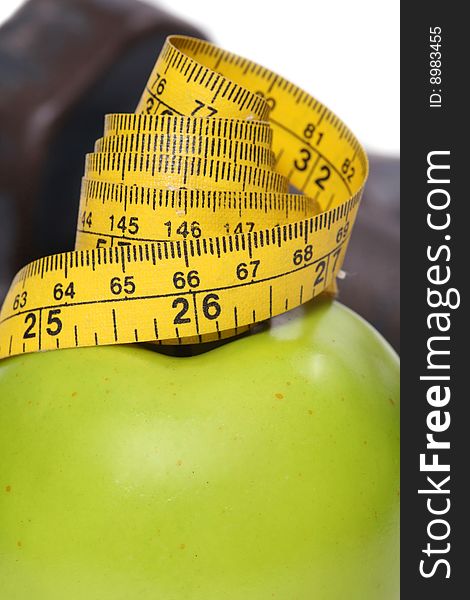 Close up of tape measure on an apple with dumbbells in the background. Close up of tape measure on an apple with dumbbells in the background