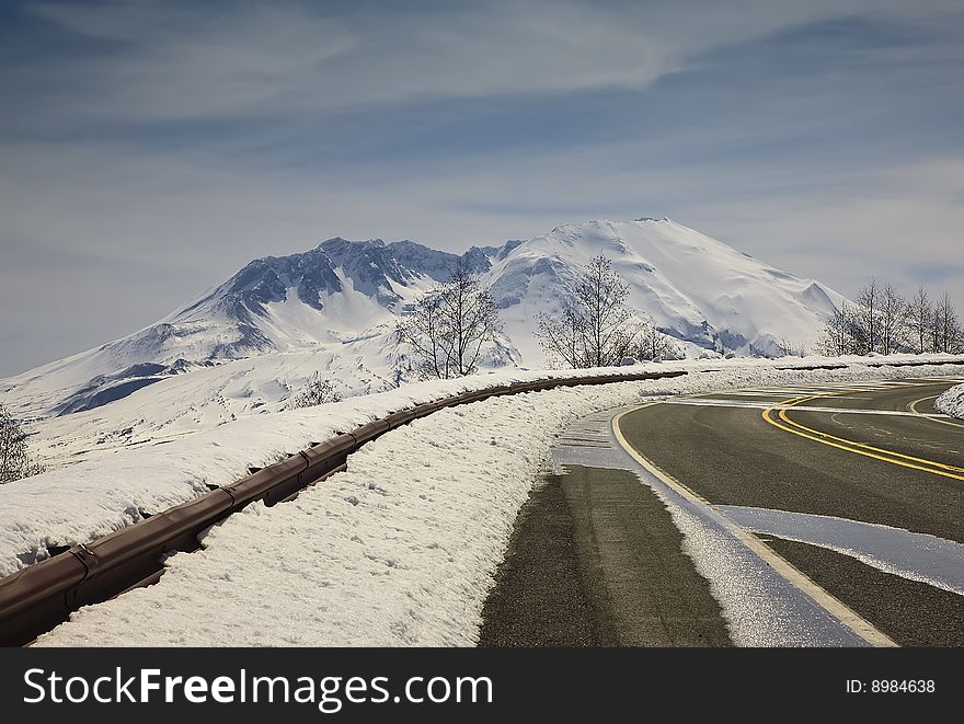Paved road with snow packed guardrail and mountains. Paved road with snow packed guardrail and mountains