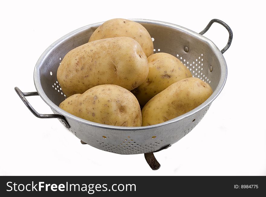 Potatoes in a metal colander on white