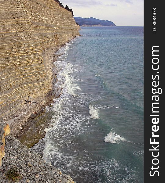 Coast of Black sea about a rock. A kind on a stony beach and the blue sea. Coast of Black sea about a rock. A kind on a stony beach and the blue sea