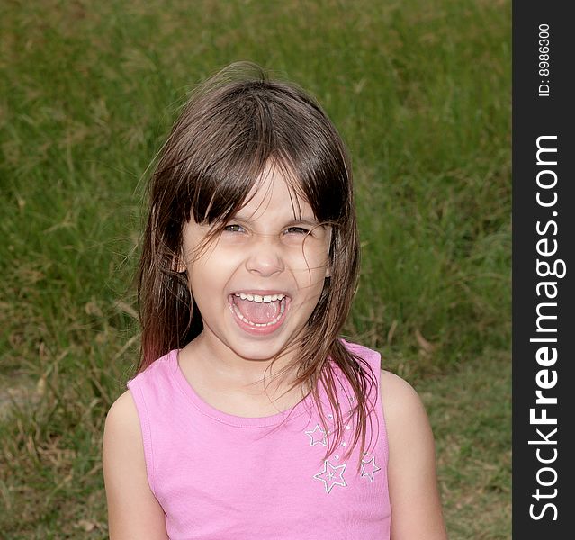 Young girl screaming in a field while playing outdoors. Young girl screaming in a field while playing outdoors.