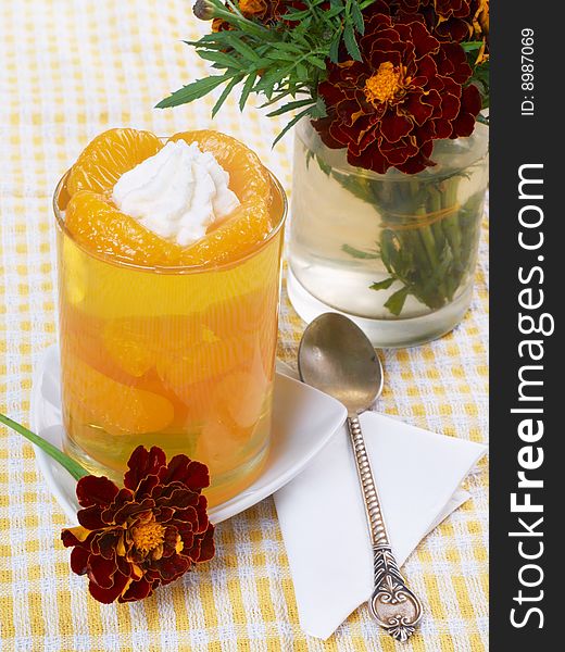 Close up of jelly with tangerines in the glass bowl toped whipped cream