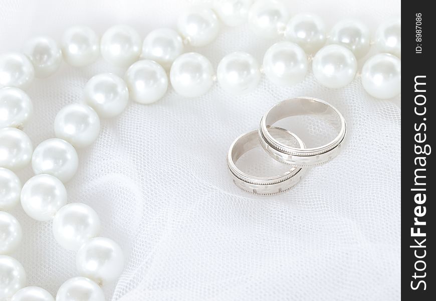 Closeup of wedding rings on a white veil