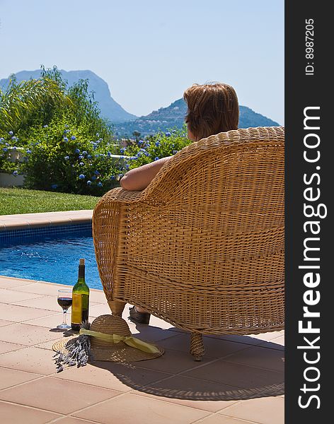 Lady relaxing in chair near pool with wine. Lady relaxing in chair near pool with wine