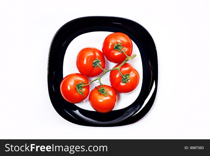 Bunch of five tomato on black and white plates. Bunch of five tomato on black and white plates
