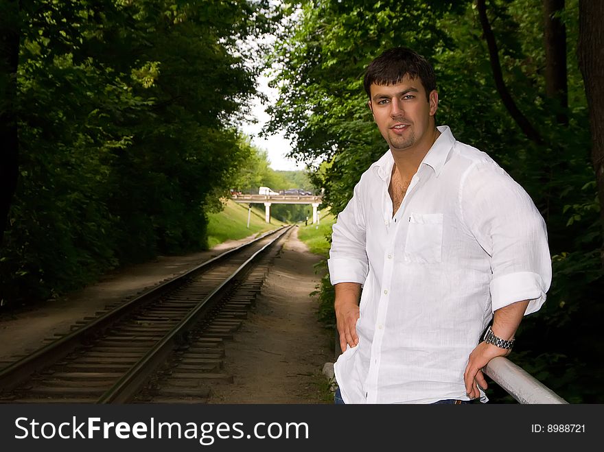 Handsome man in a white shirt against the backdrop of the railway. Handsome man in a white shirt against the backdrop of the railway