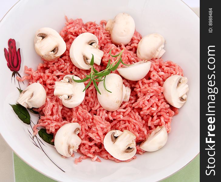 A bowl with fresh meat and white mushrooms