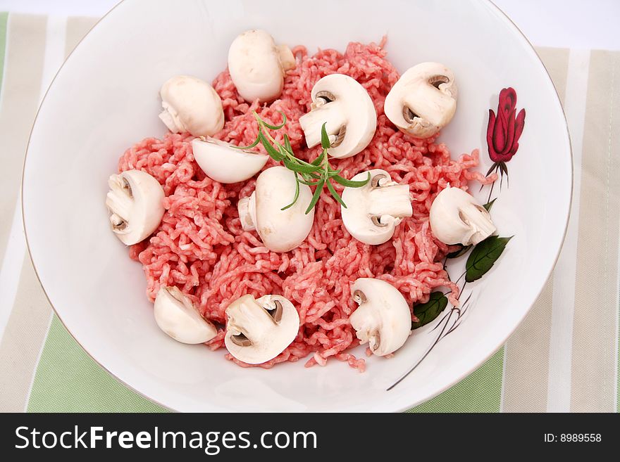 A bowl with fresh meat and white mushrooms