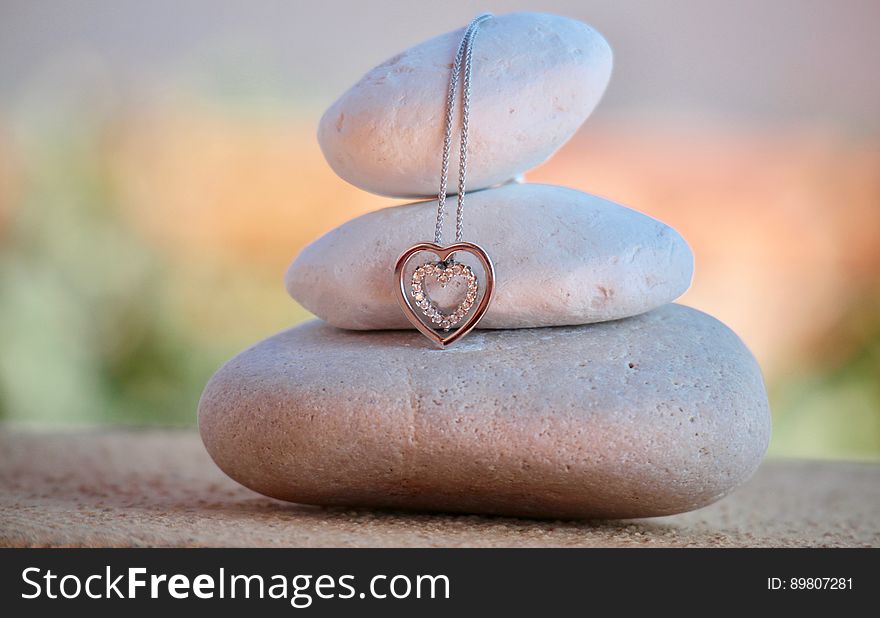 Close up of meditation stones stacked with silver and diamond heart pendant on chain with bokeh background. Close up of meditation stones stacked with silver and diamond heart pendant on chain with bokeh background.