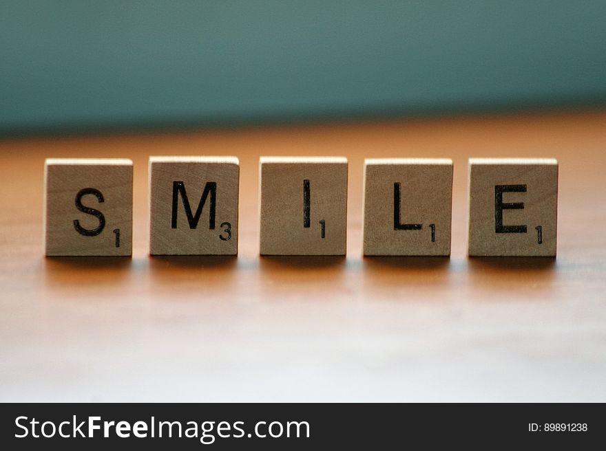 Smile spelled in wooden Scrabble tiles on wooden table. Smile spelled in wooden Scrabble tiles on wooden table.