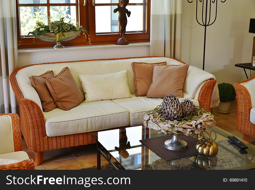 Interior of contemporary living room decorated with rattan sofa and chairs and glass top table.