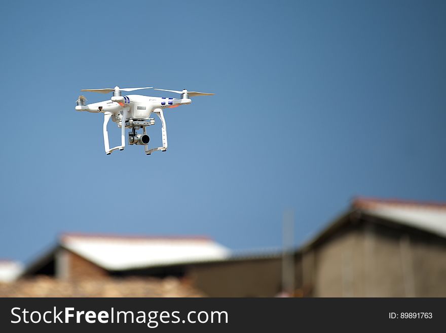 A quadcopter on the sky with houses in the background. A quadcopter on the sky with houses in the background.