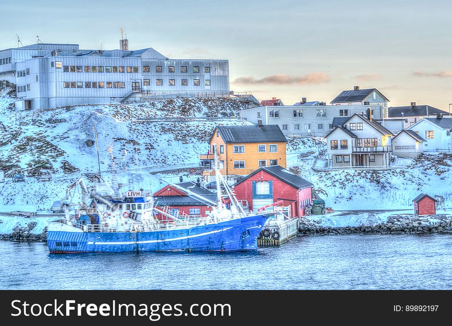 Boat docked on waterfront with colorful houses covered in snow. Boat docked on waterfront with colorful houses covered in snow.