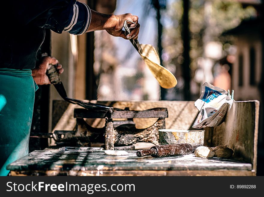 Man cooking naan on open fire outdoors.