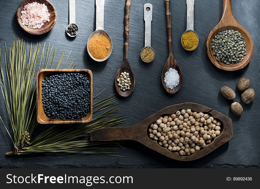 Lay flat overhead of spices in various wooden bowls and spoons on slate. Lay flat overhead of spices in various wooden bowls and spoons on slate.