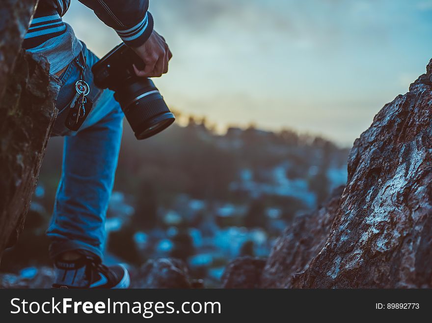 A person with a DSLR camera on the top of a mountain. A person with a DSLR camera on the top of a mountain.