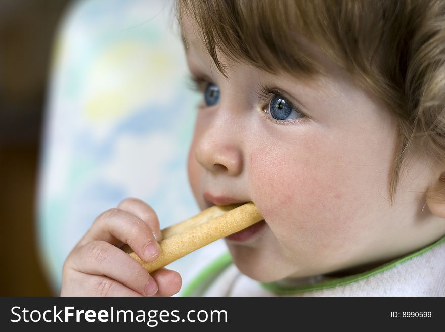A little blue-eyed child with a piece of bread in the mouth. A little blue-eyed child with a piece of bread in the mouth
