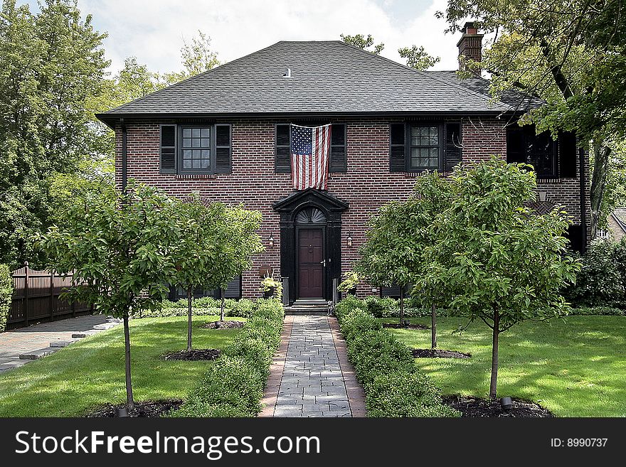 Luxury brick home in suburbs with American flag. Luxury brick home in suburbs with American flag