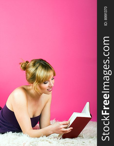 A young beautiful woman is reading on a carpet. A young beautiful woman is reading on a carpet