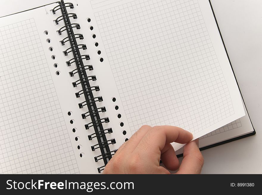 Hand turning page of blank spiral notebook (white background). Hand turning page of blank spiral notebook (white background)