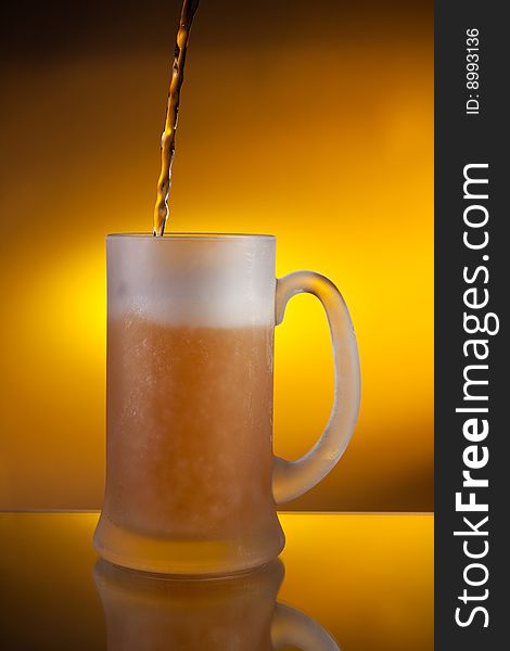 Beer pouring into a glass with yellow background