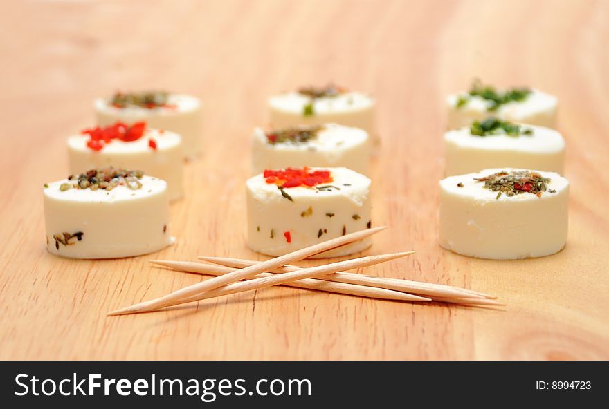 Goat cheese with herbs and toothpicks on wood board