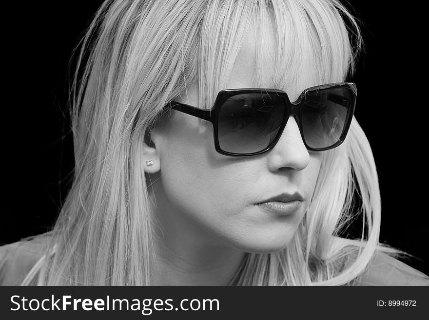 Black and White Portrait of a beautiful blond woman wearing sunglasses against black background. Black and White Portrait of a beautiful blond woman wearing sunglasses against black background