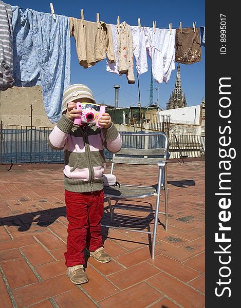 Sweet girl with pink digital camera and clothesline