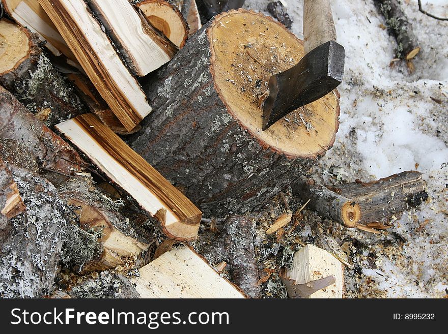 An axe and a pile of chopped wood in winter. An axe and a pile of chopped wood in winter