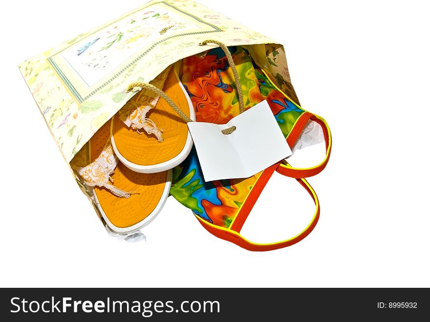 Gift bag with a colorful swimsuit and flip flop shoes in it, isolated on a white background. Gift bag with a colorful swimsuit and flip flop shoes in it, isolated on a white background.