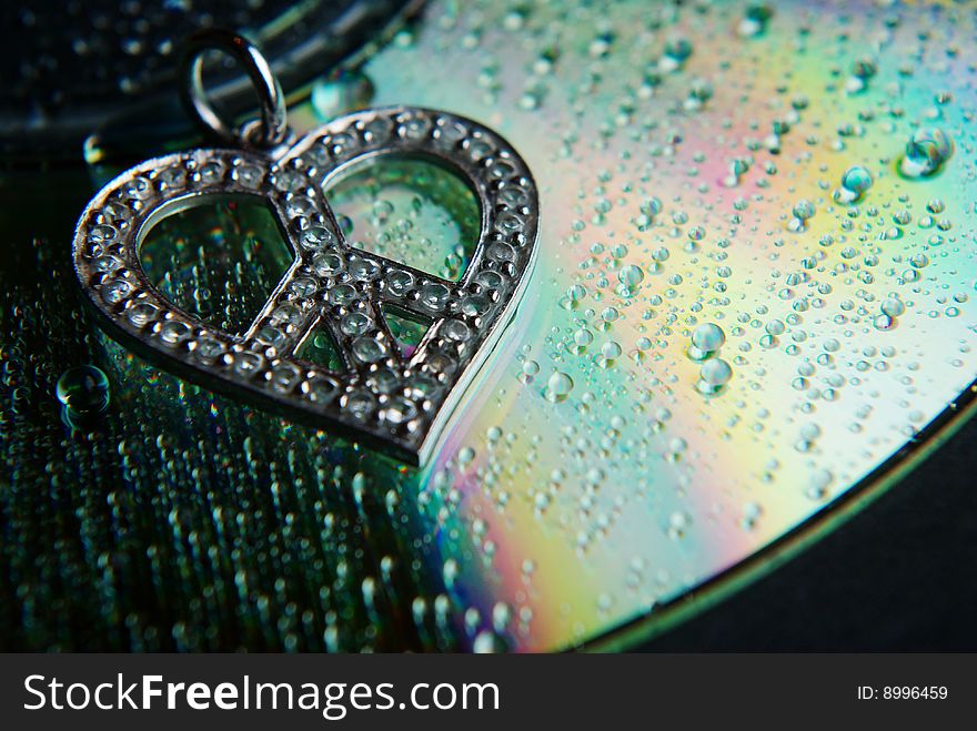 Tiny diamonds highlight this pendant resting upon a CD capturing light and splitting into a rainbow. Water droplets further magnify. Tiny diamonds highlight this pendant resting upon a CD capturing light and splitting into a rainbow. Water droplets further magnify.
