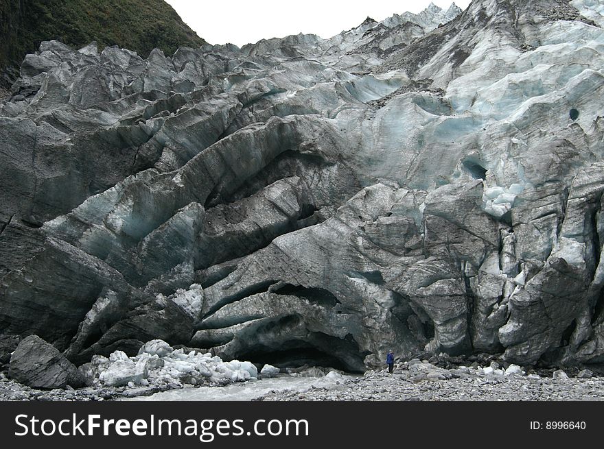 Little blue man standing in front of a big blue glacier. Little blue man standing in front of a big blue glacier