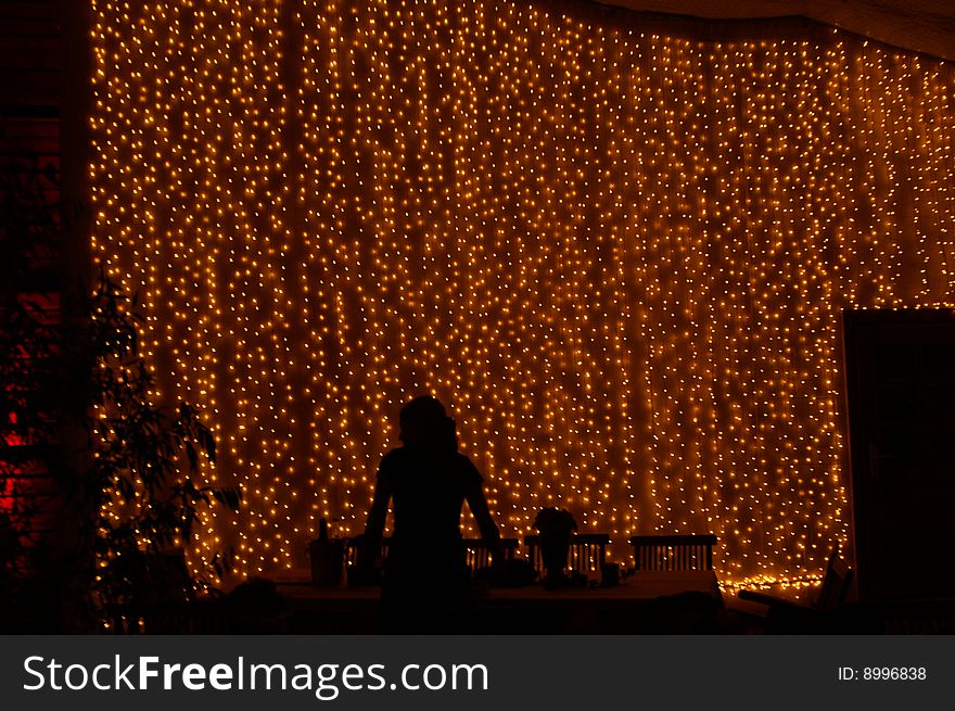 Silhouette of a person standing in front of a curtain of lights. Silhouette of a person standing in front of a curtain of lights