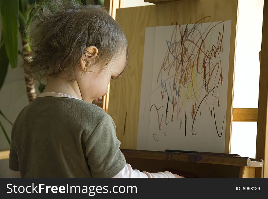 Small artist drawing at a wooden easel. concentrate. Small artist drawing at a wooden easel. concentrate